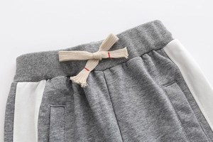 Detail of boys' grey joggers showing elastic waistband and contrast side stripes