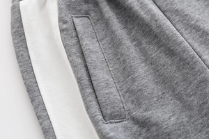 Macro shot of grey cotton jogger pants with white side stripe and pocket stitching
