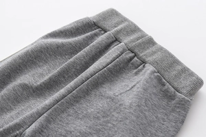 Close-up of boys' grey sports pants featuring elastic ribbed waistband and side stripes
