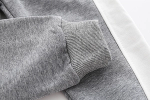 Detail of grey knitted joggers featuring elastic ribbed cuffs and side white stripes