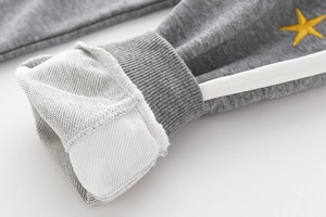 Detail of grey jogger cuff with white side stripes and yellow star embroidery