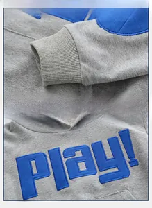 Detail of grey kids hoodie showing ribbed cuffs and blue PLAY letter embroidery