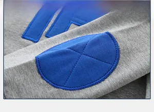 Close-up of gray knit kids hoodie featuring premium blue embroidered letter patch