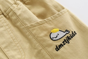 Detail of boys khaki cotton shorts with elastic waistband and whale embroidery