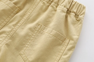 Detail view of khaki cotton shorts featuring elastic waistband and square patch pocket