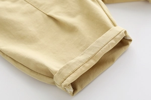 Macro shot of khaki cotton twill fabric with double-rolled hem detail on boys' shorts