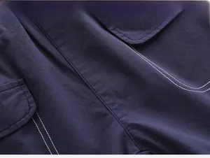 Detailed macro view of navy blue fabric texture with white contrast stitching on pocket