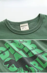 Détail d'un t-shirt enfant en coton vert avec col rond et imprimé graphique de dinosaure
