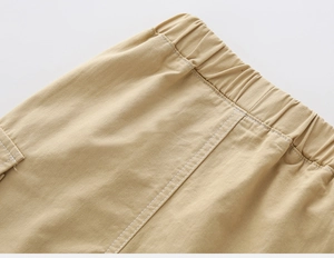 Detailed close-up of khaki cargo shorts showing elastic waist and white contrast stitching