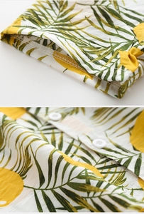 Detailed view of tropical palm leaf print on cotton fabric with white buttons