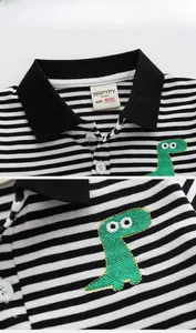 Close-up of boys black and white striped polo shirt with green dinosaur embroidery detail