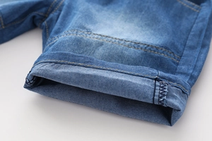 Détail de l'ourlet replié sur un short en jean pour garçon avec double couture jaune