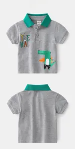 Detail of grey polo shirt with green collar and cartoon crocodile surfing print