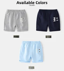 Flat lay of three soft cotton kids shorts in grey, navy, and sky blue with dinosaur motifs