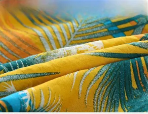 Close-up of tropical palm leaf print on yellow breathable fabric for kids shirts