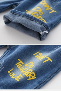 Detailed close-up of boys' denim shorts with yellow letter print and washed fabric texture