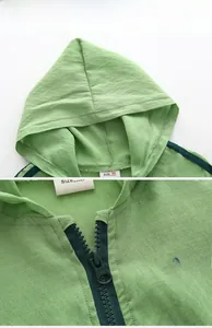 Detail of green kids hooded sun protection jacket with zipper and chest lettering