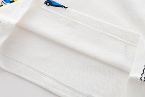 Dettaglio polo bianca da bambino in cotone piqué con stampa di auto blu e cuciture