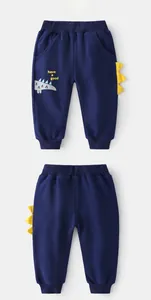 Dettaglio dei pantaloni sportivi blu navy per bambini con stampa dinosauro e creste
