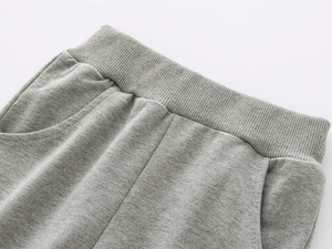 Detailed shot of grey kids sweatpants showing ribbed elastic waistband and dual pockets