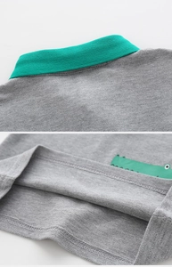 Detail of grey polo shirt featuring lime green ribbed collar and cartoon crocodile print