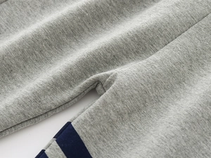 Detailed close-up of stitching and blue stripes on grey knit cotton joggers for boys
