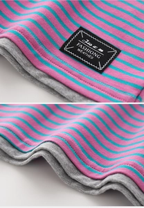 Detailed view of striped cotton fabric with fashion patch and faux layered hem