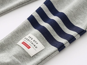 Detail of grey knitted kids sports pants featuring navy stripes and a vintage label patch