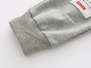 Detailed close-up of grey kids joggers with ribbed cuffs and stitched logo labels