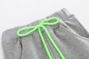 Detail of gray kids joggers featuring elastic ribbed waistband and neon green drawstring