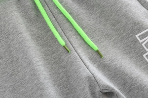 Close-up of children's grey knit joggers with vibrant neon green drawstrings and texture