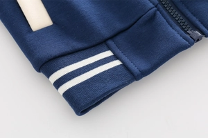 Detail of navy boy's baseball jacket showing ribbed hem and smooth zipper texture