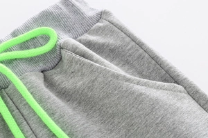 Detail of gray kids joggers with ribbed waist and fluorescent green drawstring accent