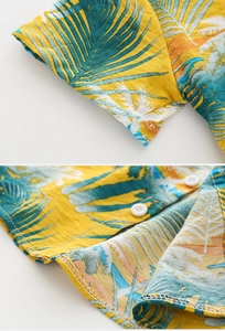 Detailed view of the tropical palm print fabric and fine stitching on the boy's beach shirt