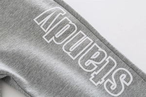 Detail of gray cotton joggers featuring white APUEIS lettering and textured fabric