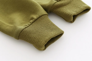 Gros plan des poignets côtelés vert olive sur le sweat-shirt dinosaure pour enfant en coton