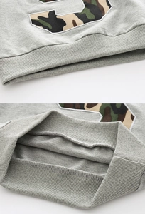 Makro-Detail des grauen Jungen-Sweatshirts mit Camouflage-Stickerei und Rippbündchen