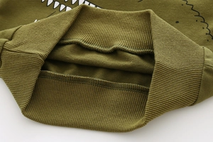 Détail macro du sweat-shirt dinosaure vert olive montrant le col côtelé et les coutures de qualité