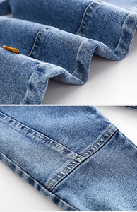 Detail von blauem Denim-Stoff mit gelben Kontrastnähten und gewebtem Etikett für Jungenhosen