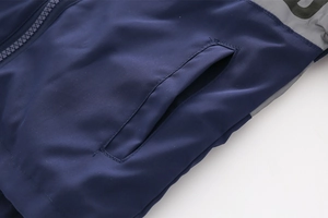 Detail of blue winter jacket showing smooth zipper, side pocket and gray letter print
