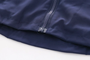 Macro detail of high-quality zipper and hem on a navy blue hooded jacket for children
