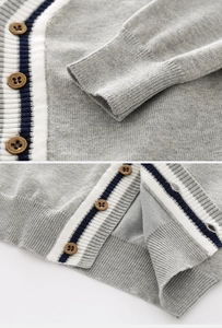 Détail du cardigan gris en maille avec bordures rayées et boutons en bois rétro