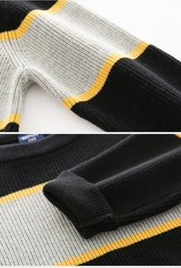 Close-up of thick knit sweater showing black grey and yellow striped texture and ribbed cuffs