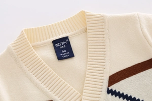 Macro view of V-neck collar detail on kids' beige knit cardigan with diamond patterns