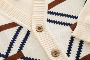 Detail of V-neck knitted cardigan showing dark wood grain buttons and geometric patterns