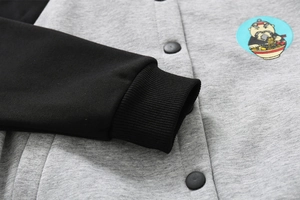 Detail of toddler fleece jacket showing grey knit fabric, black snap buttons and embroidery
