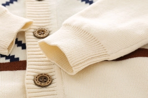 Close-up of children's knit cardigan featuring vintage wooden buttons and ribbed cuffs