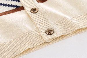 Detail of soft cream knit cardigan with zigzag geometric patterns and wooden buttons