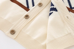 Close-up of fine knit cardigan featuring blue wave patterns and brown buttons detail