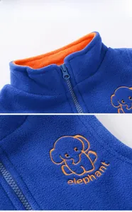 Détail de gilet polaire enfant avec broderie éléphant orange et fermeture éclair à col